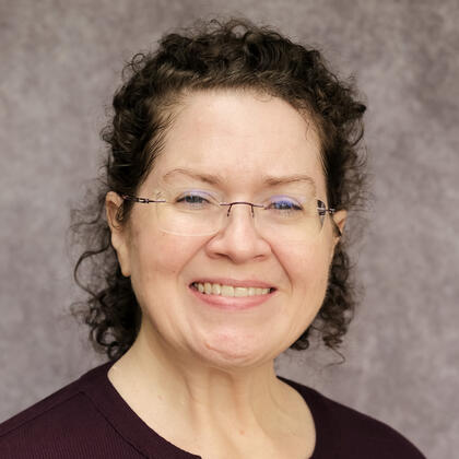 Headshot of Nikki Rehman, a smiling woman with short, curly hair and glasses.